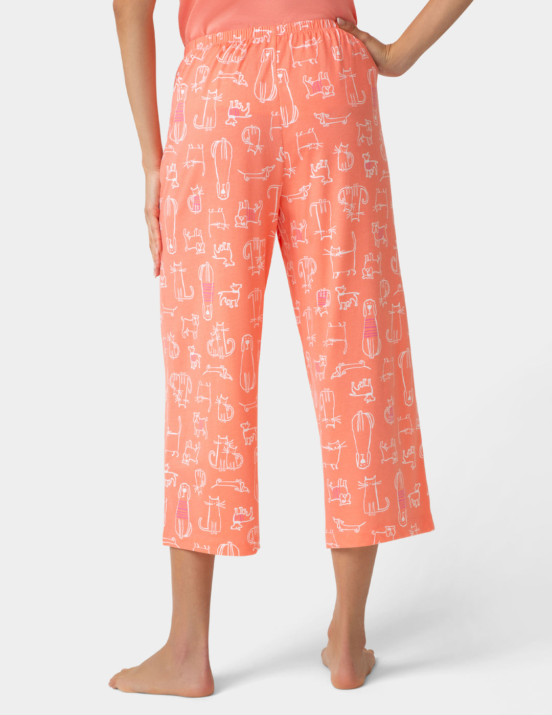 Person wearing coral capri pants with white graphic design on a white background