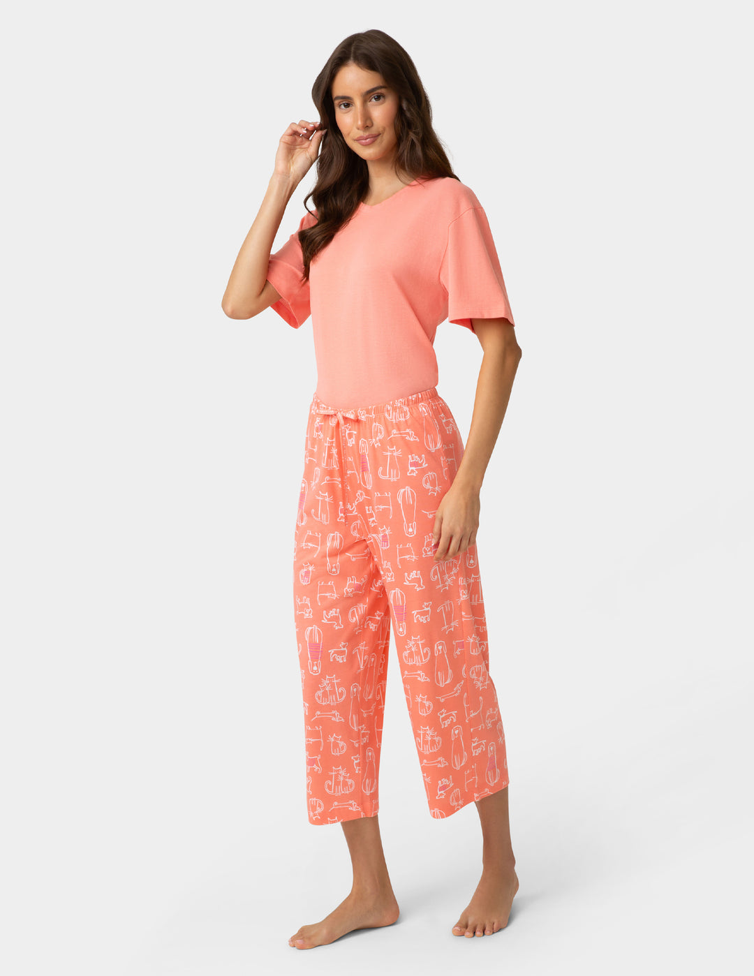 Woman wearing a coral pajama set with a white background