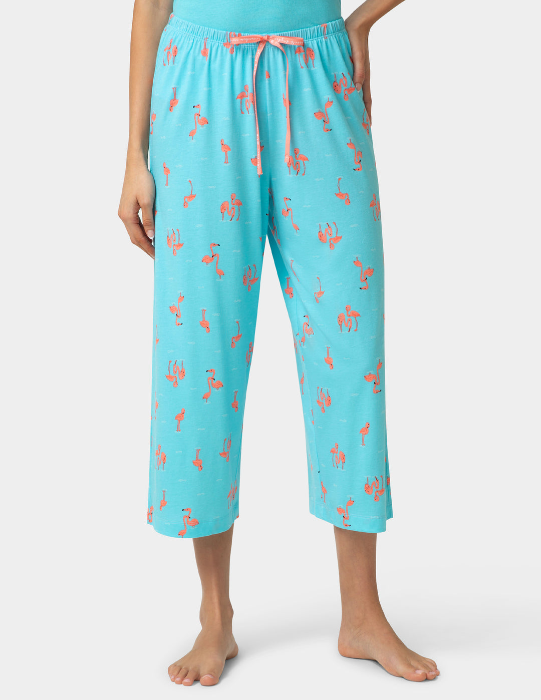 Person wearing turquoise capri pajama pants with a design on a white background