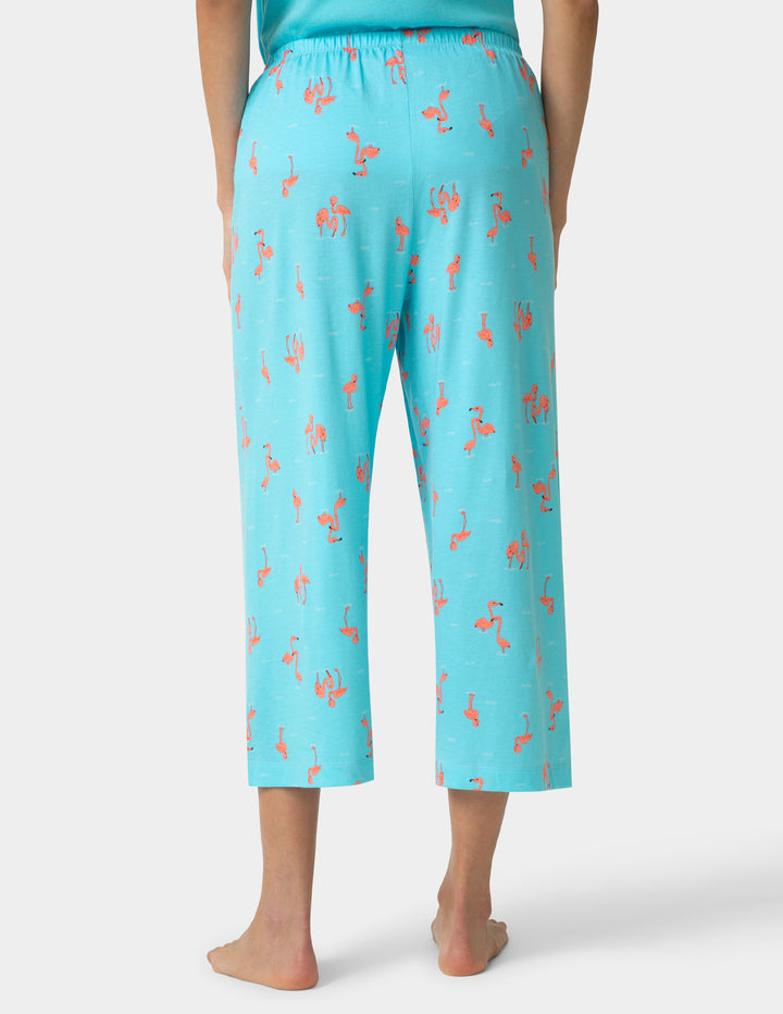 Person wearing turquoise capri pants with a pattern on a white background