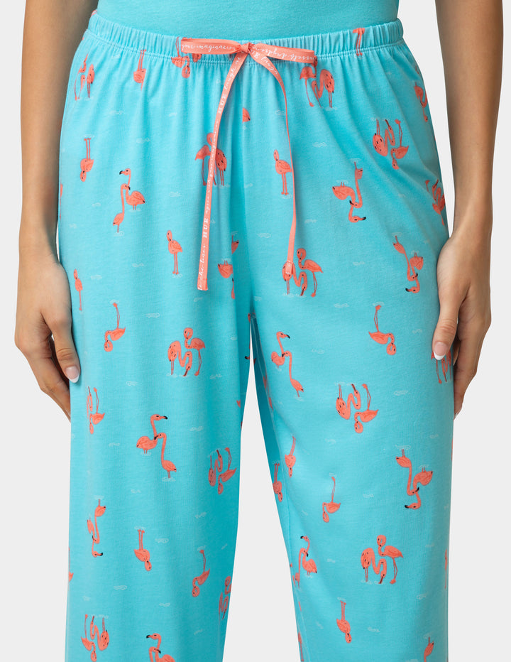 Turquoise pajama pants with pink flamingo pattern on a white background