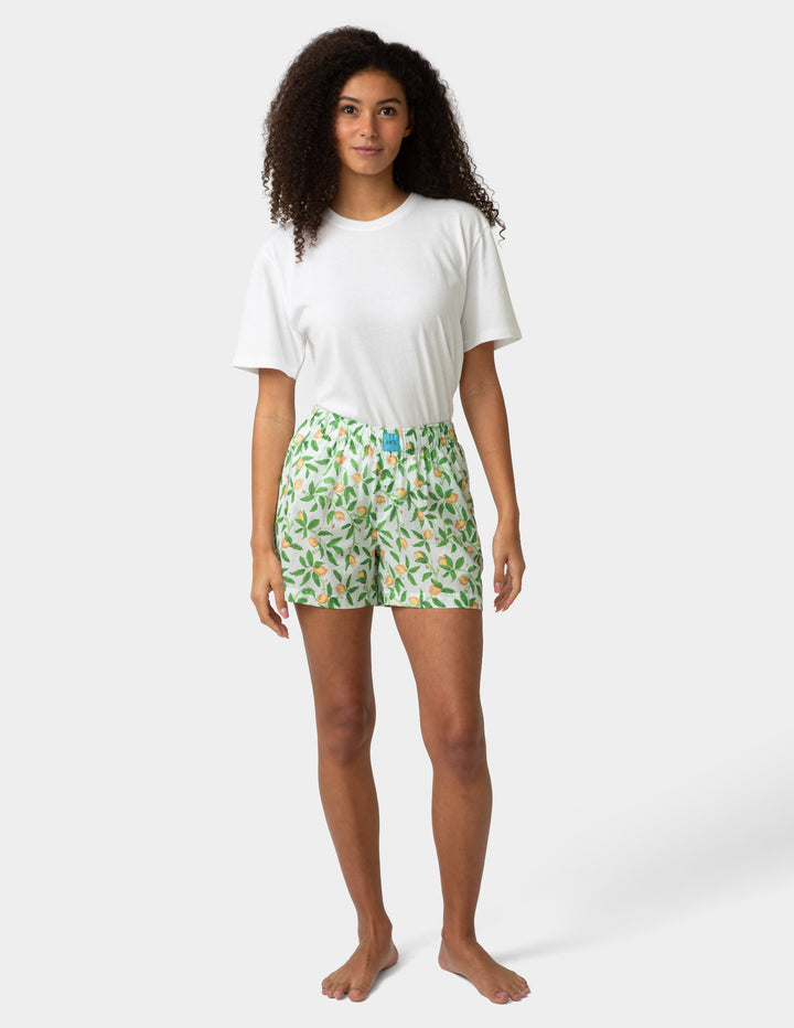 Woman wearing a white t-shirt and green floral pj boxers on a white background