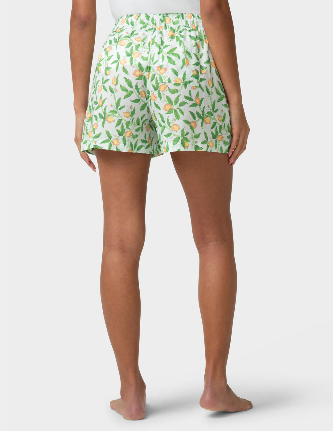 Woman wearing green floral pj boxers on a white background
