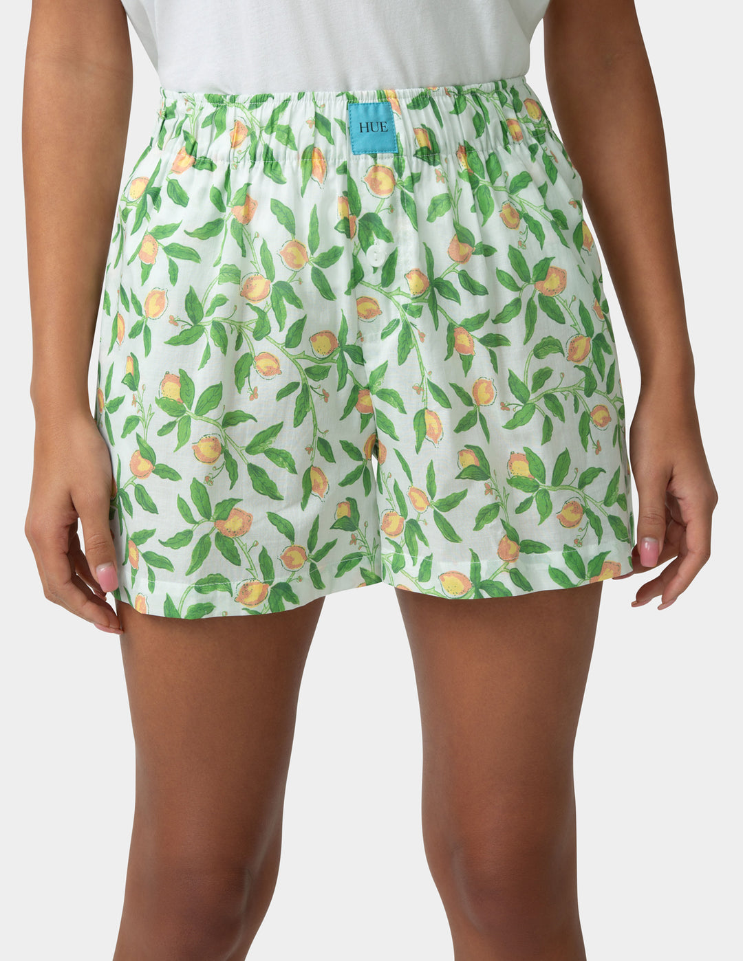 Woman wearing pj boxers with a fruit pattern on a plain background