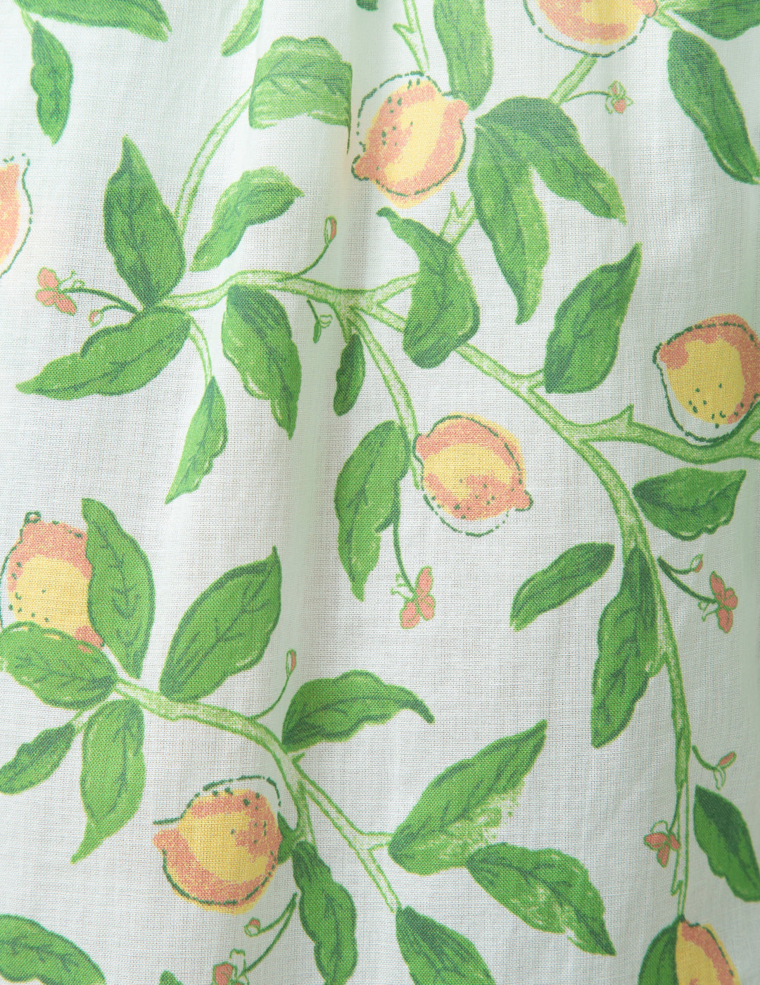 Fabric with a pattern of green leaves and lemons on a white background