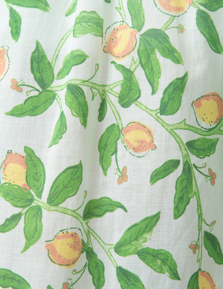 Fabric with a pattern of green leaves and lemons on a white background