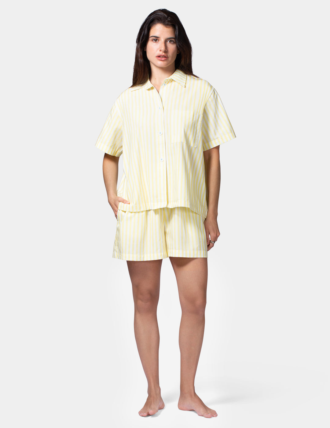 Woman wearing a light yellow pajama set on a white background