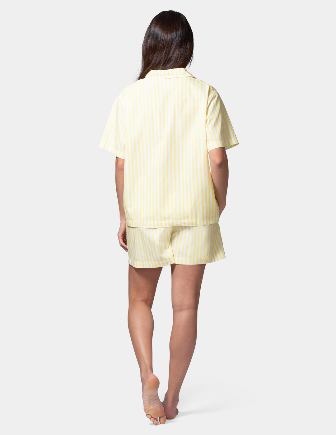 Woman wearing a yellow striped pajama set on a white background