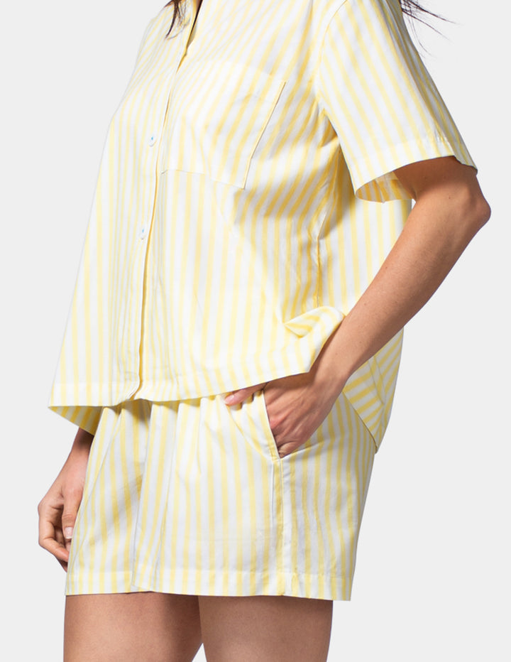 Woman wearing a yellow striped pajama set on a white background
