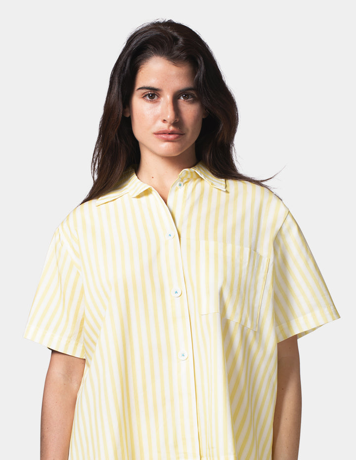 Woman wearing a yellow and white striped shirt against a plain background