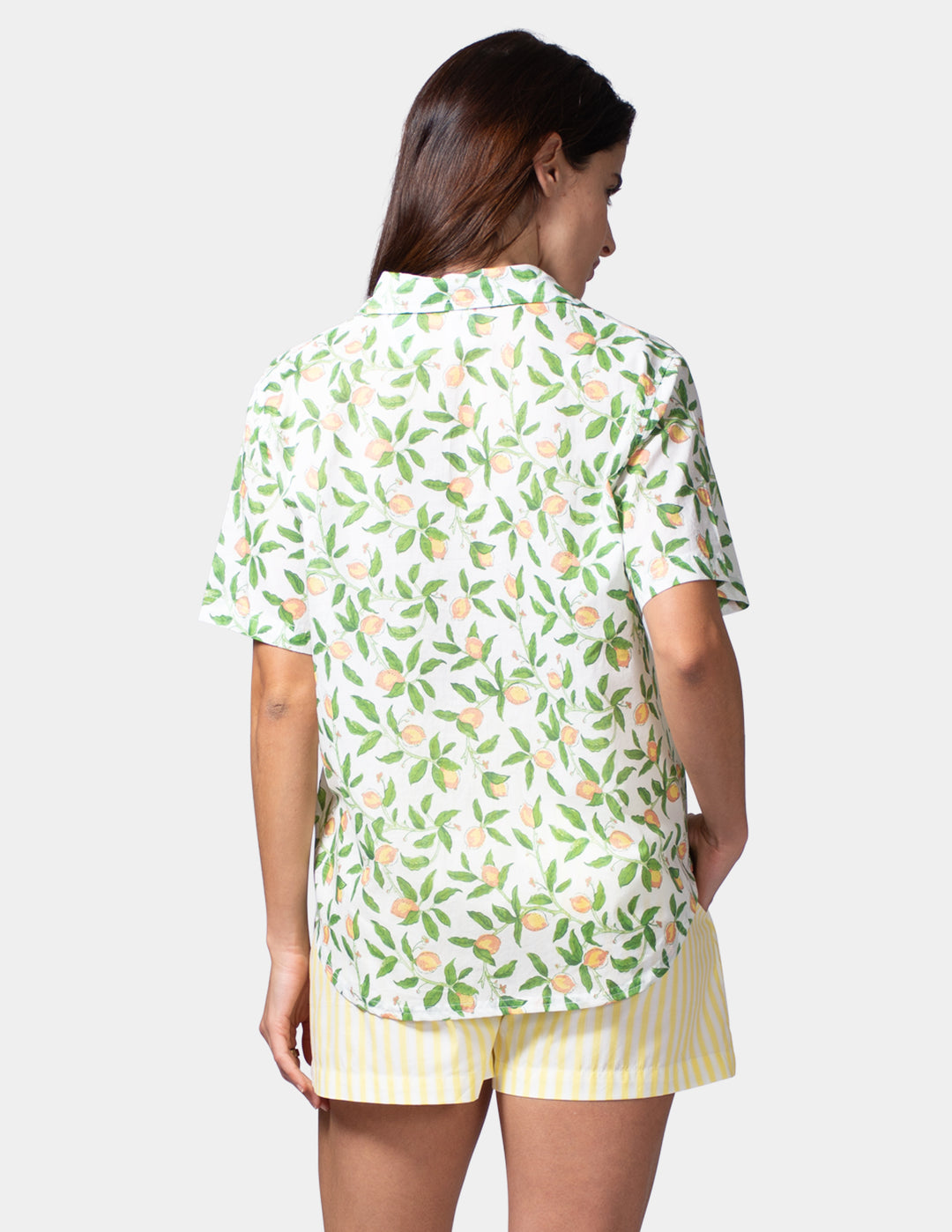 Woman wearing a lemon shirt and yellow shorts on a white background