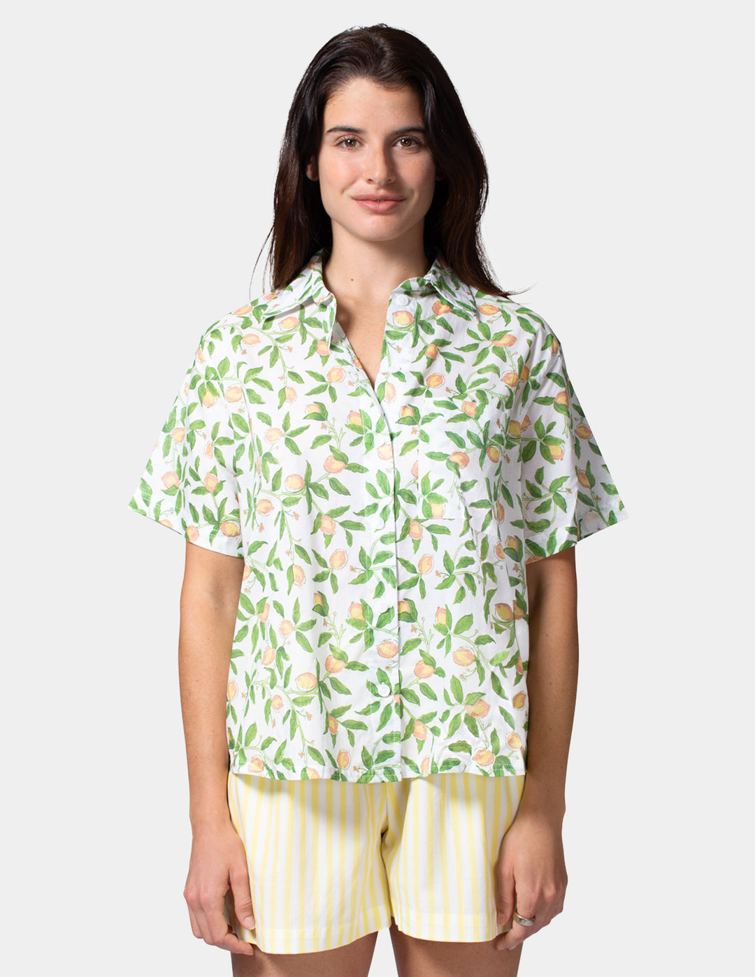 Woman wearing a patterned shirt and yellow shorts on a white background