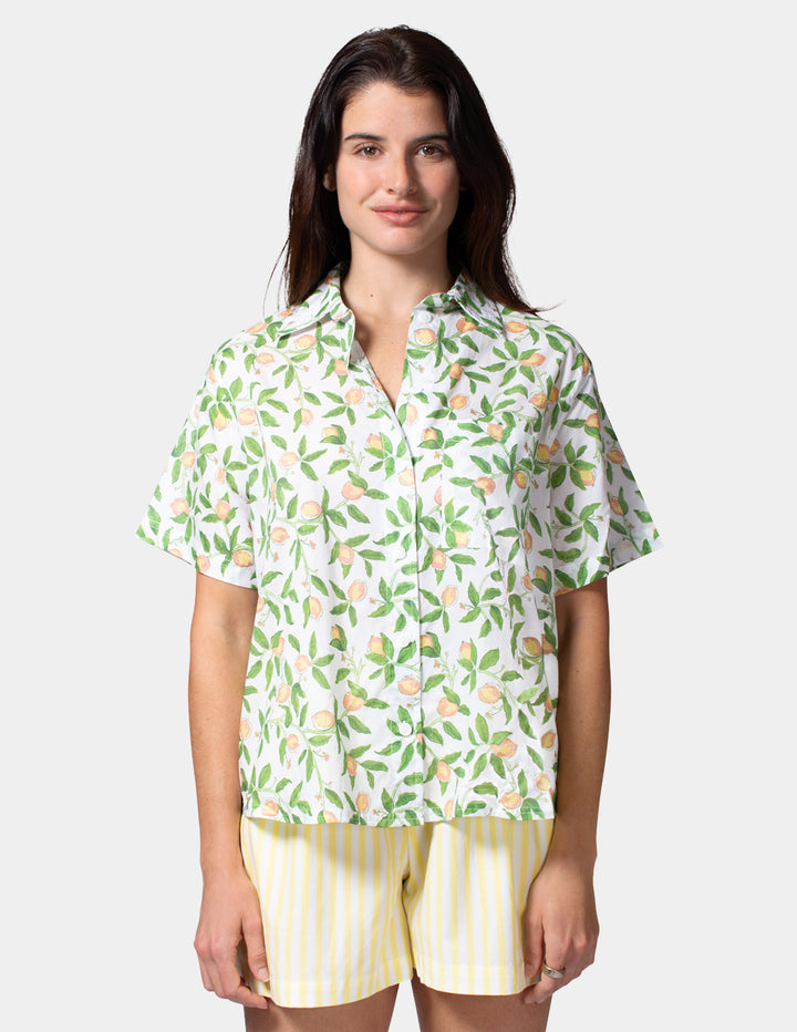 Woman wearing a patterned shirt and yellow shorts on a white background