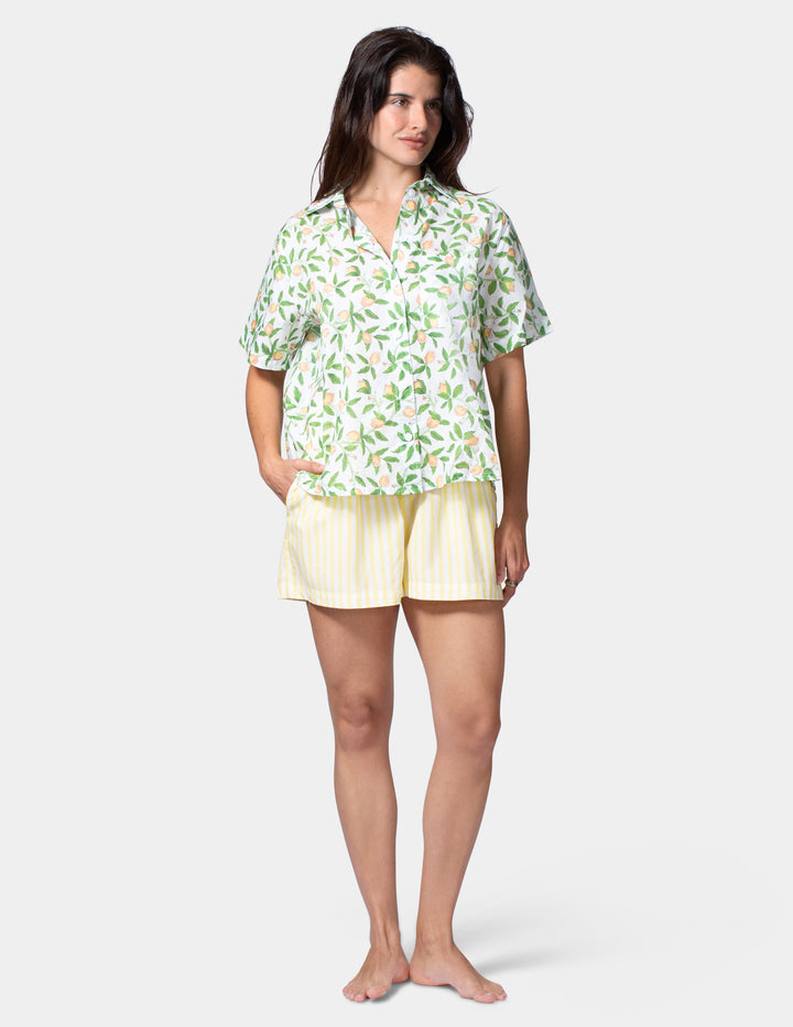 Woman wearing a lemon shirt and yellow shorts on a white background