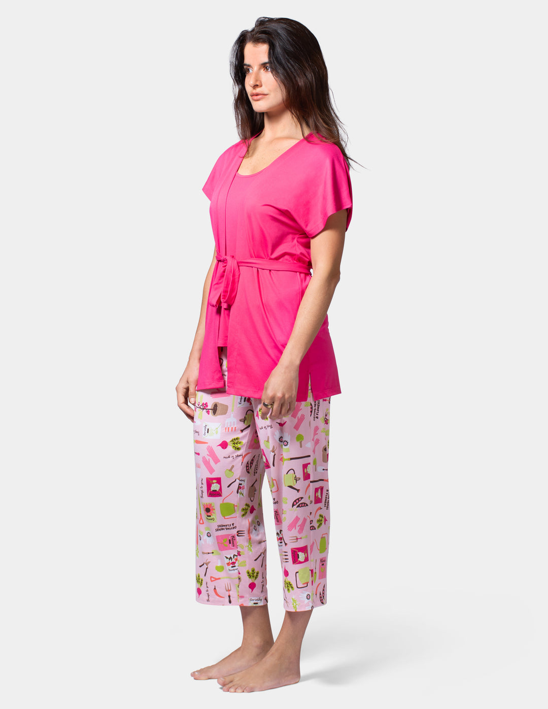 Woman wearing a pink robe and patterned pajama pants on a white background