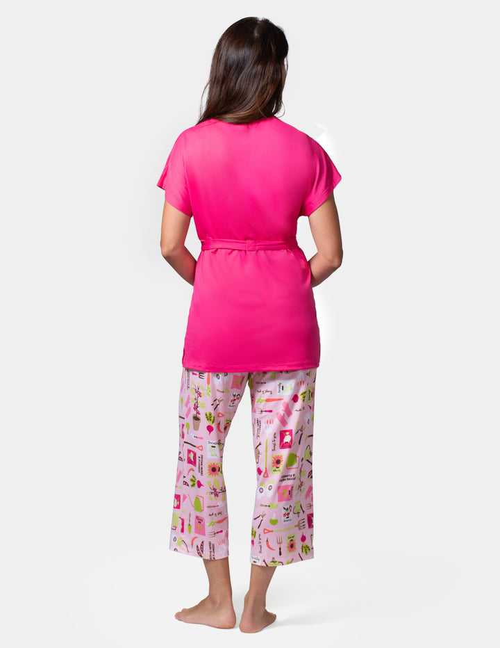 Woman wearing a pink top and patterned pants on a white background