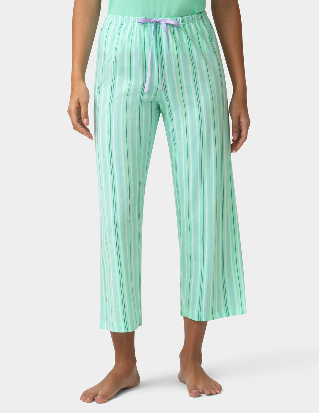 Person wearing green striped pajama pants on a white background