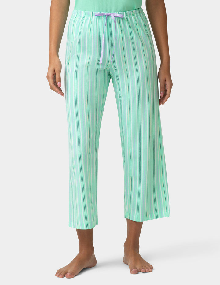 Person wearing green striped pajama pants on a white background