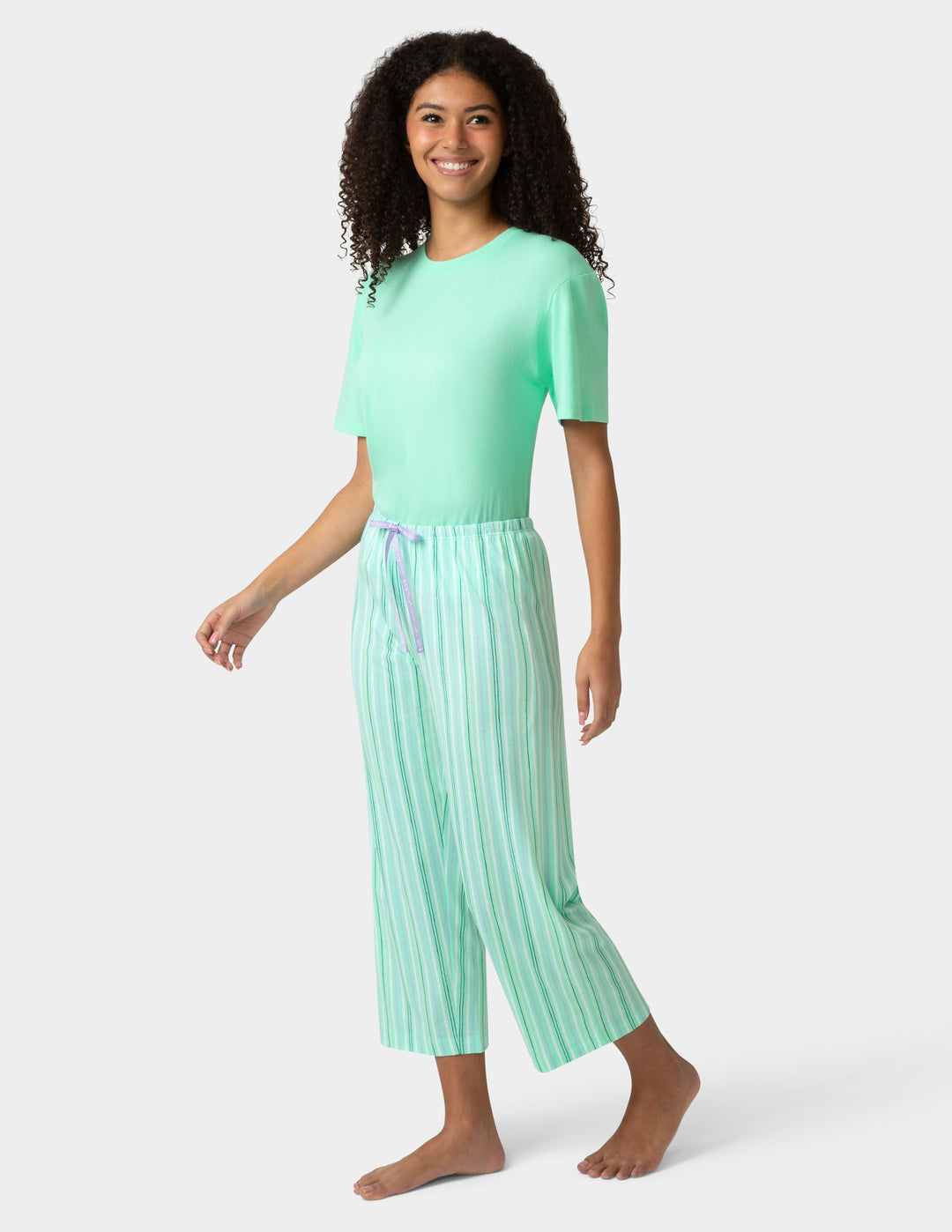 Woman wearing a mint green top and striped pants on a white background