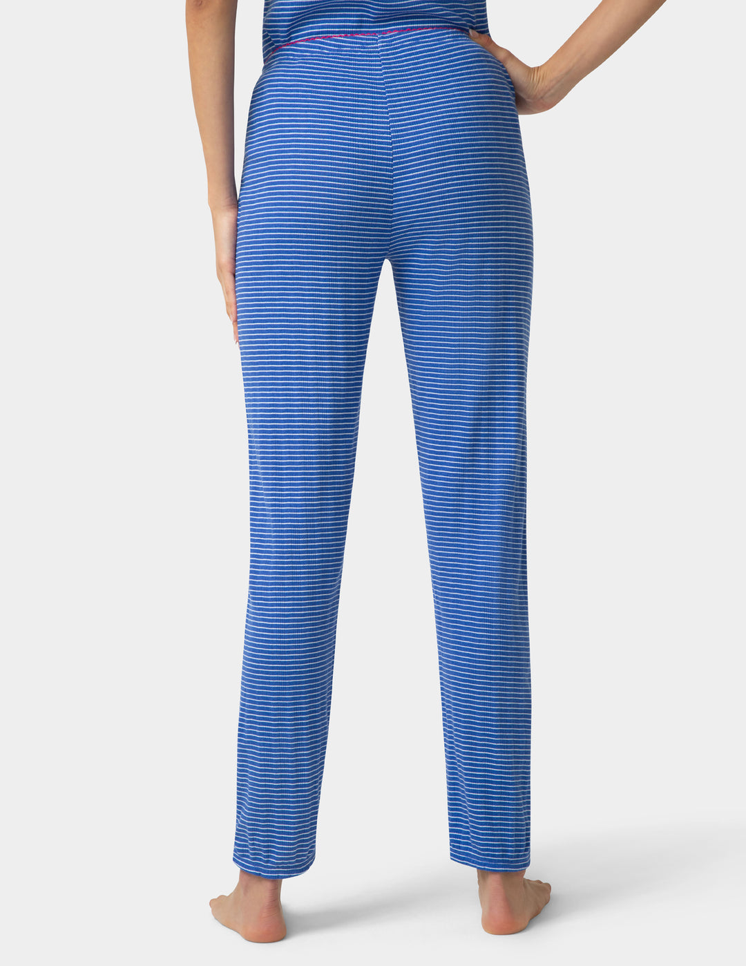 Woman wearing a blue striped pajama jogger backside view on a white background 