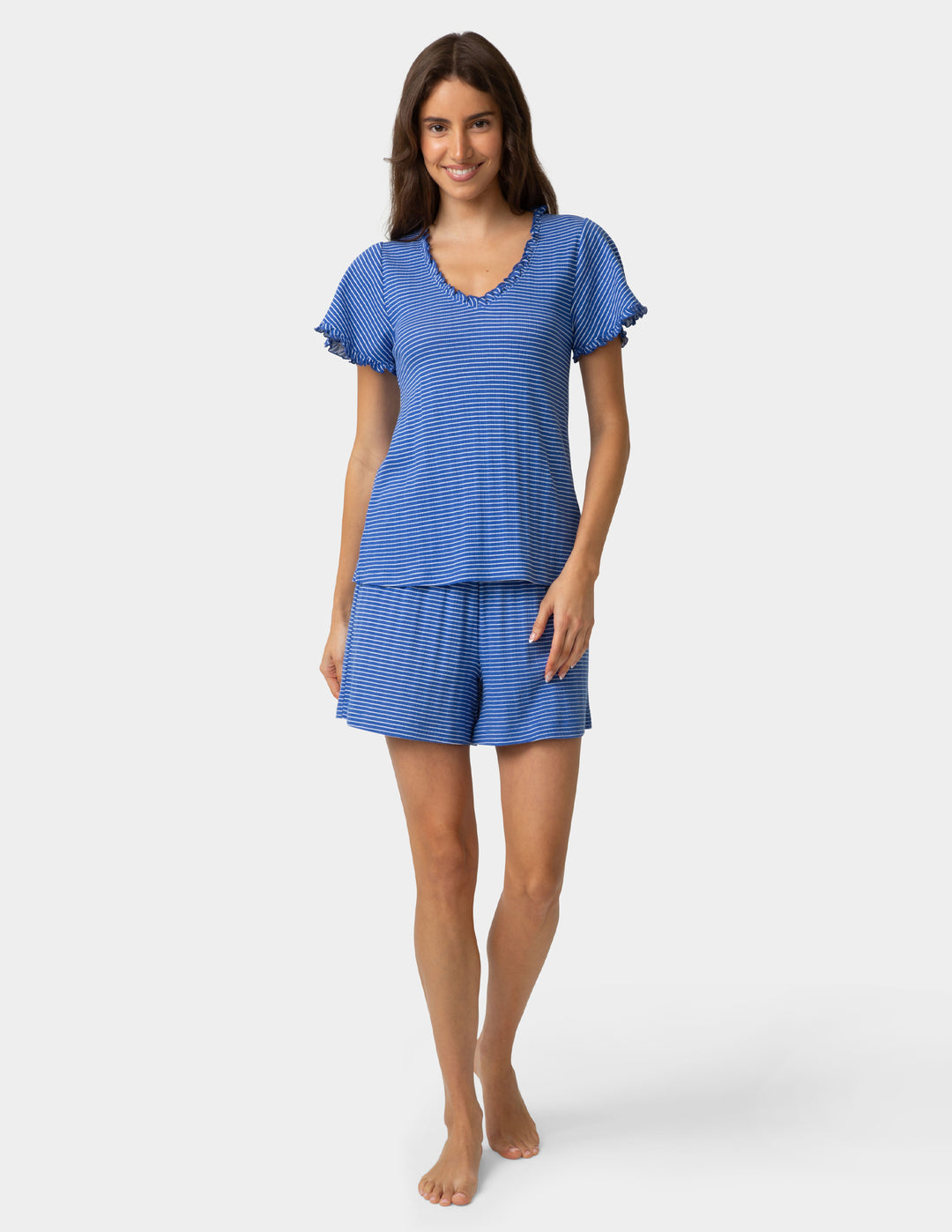 Woman wearing a blue striped pajama tee and boxer shorts on a plain background