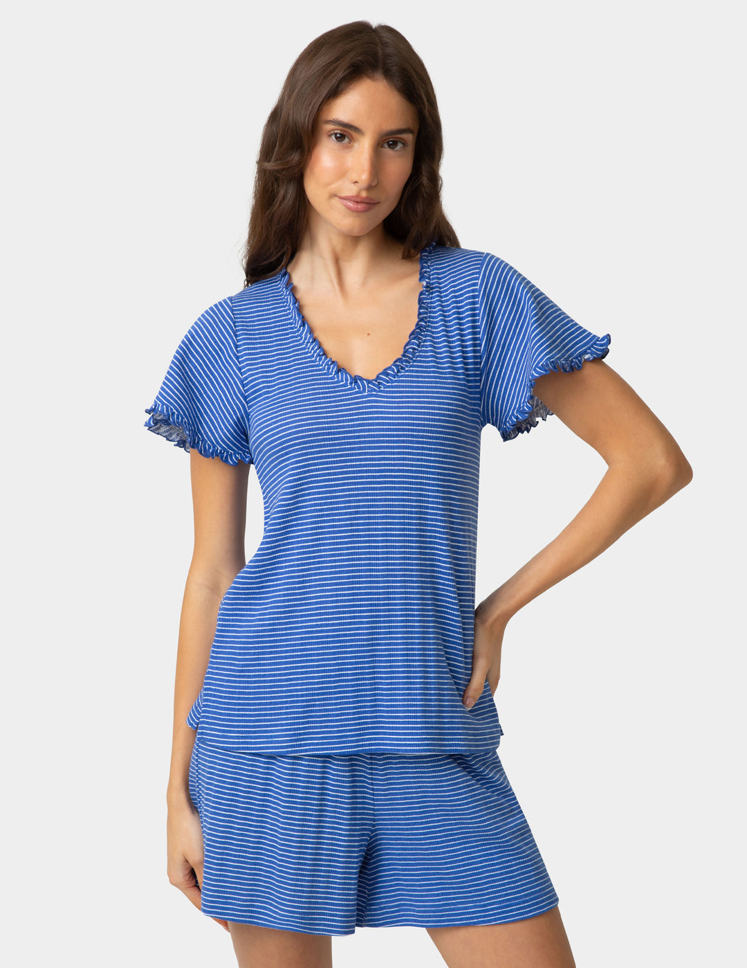 Woman wearing a blue striped pajama tee and boxer shorts on a plain background