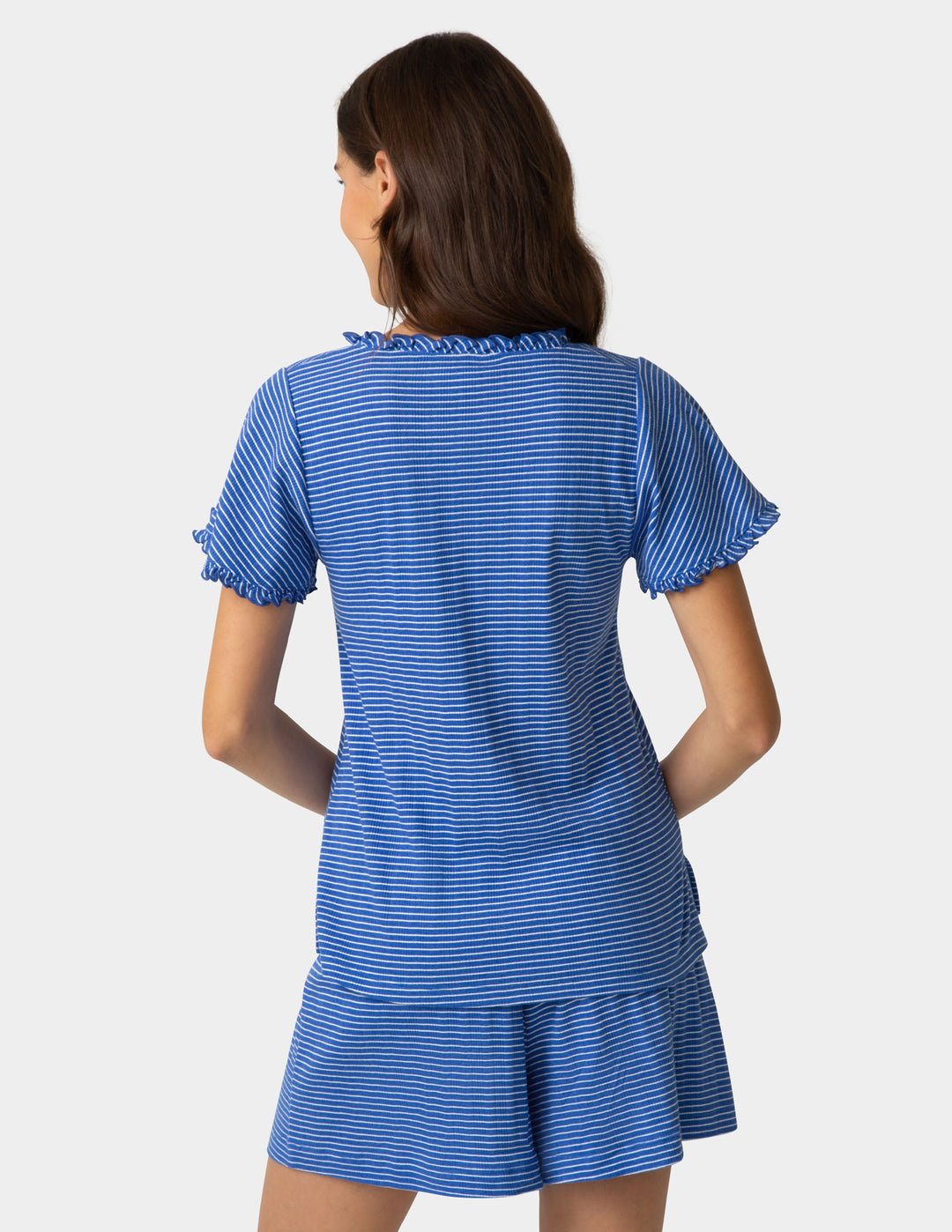 Woman wearing a blue striped pajama tee and boxer shorts backside view on a plain background