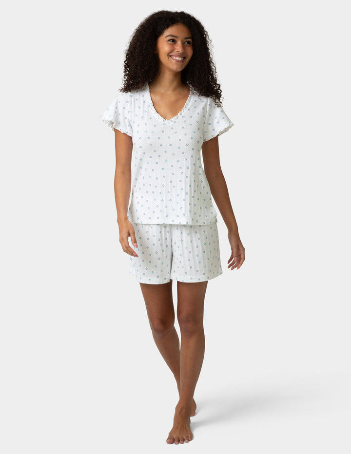 Woman wearing a pajama tee and boxer set with a small shell pattern on a plain background