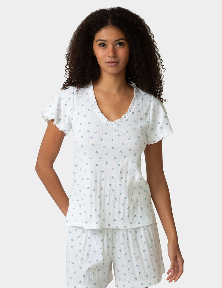 Woman wearing a pajama tee and bottoms set with a small shell pattern on a plain background