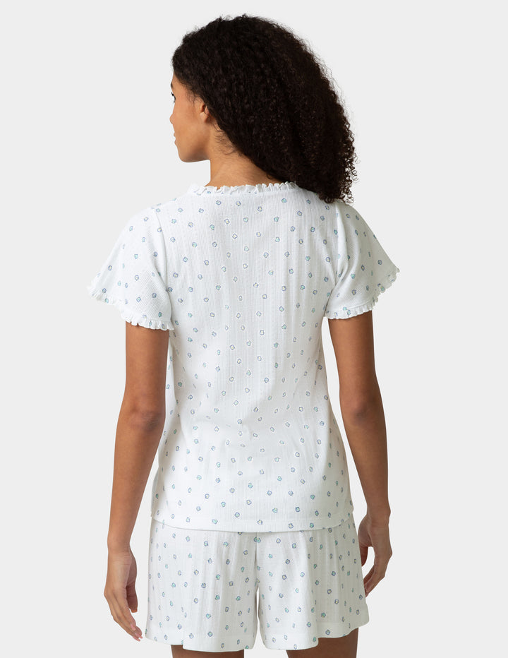Woman wearing a pajama tee and boxer set with a small shell pattern, backside view, on a plain background