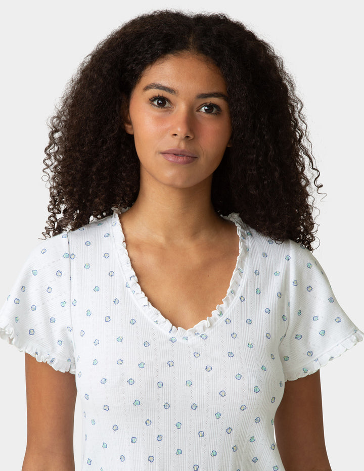 Woman wearing a pajama tee with a small shell pattern on a plain background