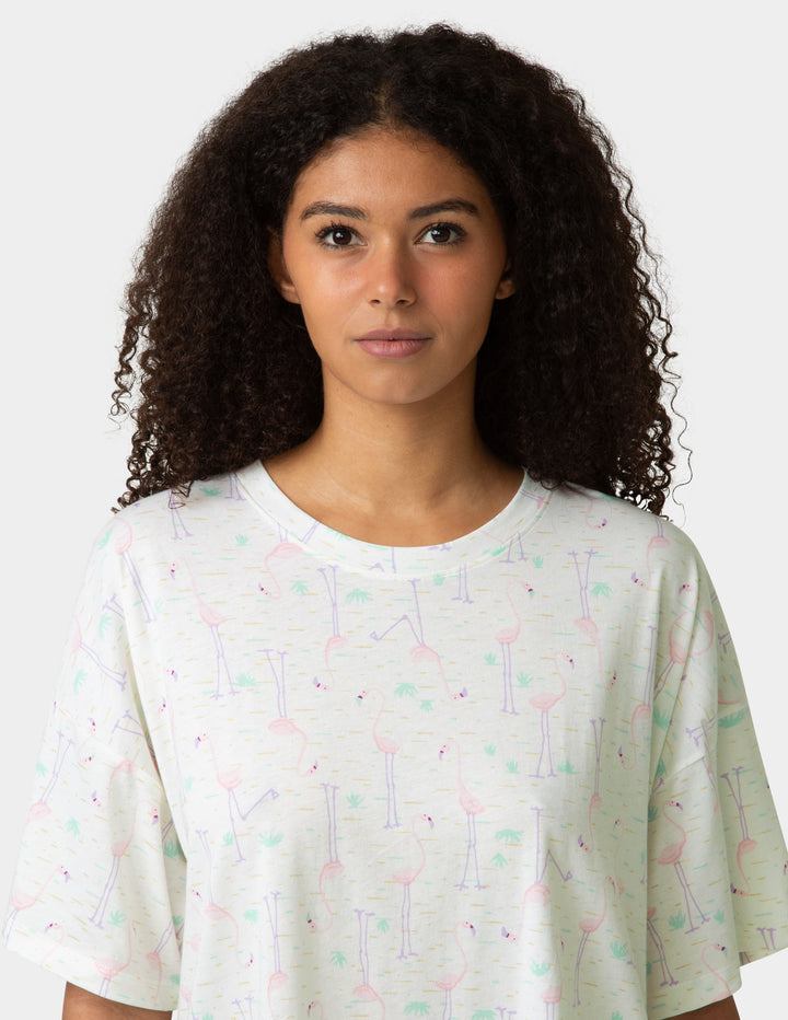 Woman wearing a white t-shirt with colorful patterns on a plain background
