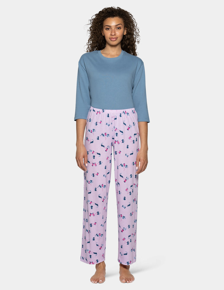 A model wearing light purple pajama pants with a cat pattern, paired with a light blue top against a light gray background.