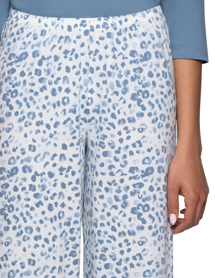 Close-up of a person wearing wide-leg pajama pants with a blue and white leopard print pattern, paired with a light blue top.