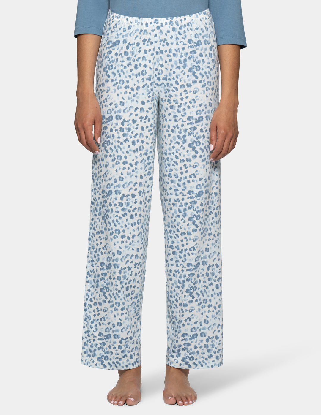 A model wearing high-waisted, wide-leg pajama pants with a blue and white abstract leopard print, paired with a light blue top, shown against a light gray background.