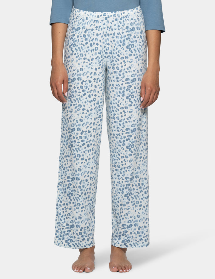A model wearing high-waisted, wide-leg pajama pants with a blue and white abstract leopard print, paired with a light blue top, shown against a light gray background.