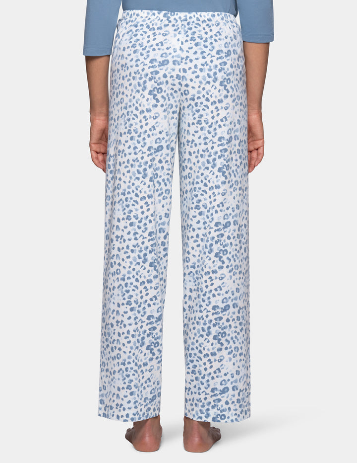 A model shown from the back wearing high-waisted, wide-leg pajama pants with a blue and white abstract leopard print, paired with a light blue top, shown against a light gray background.