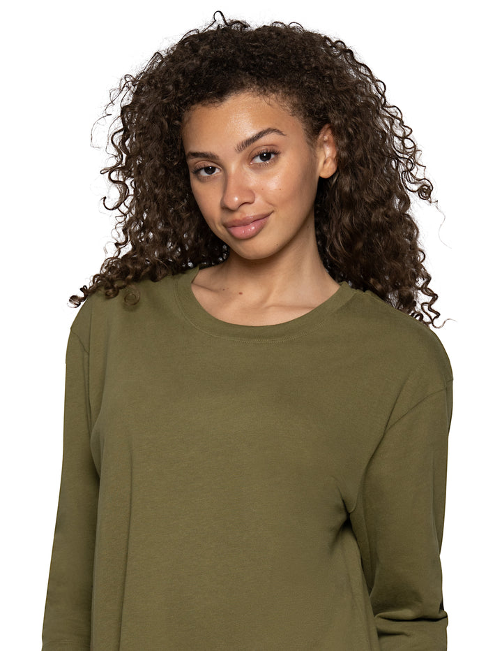 A woman with curly brown hair wearing a long-sleeve crewneck top in olive green, shown against a plain white background.