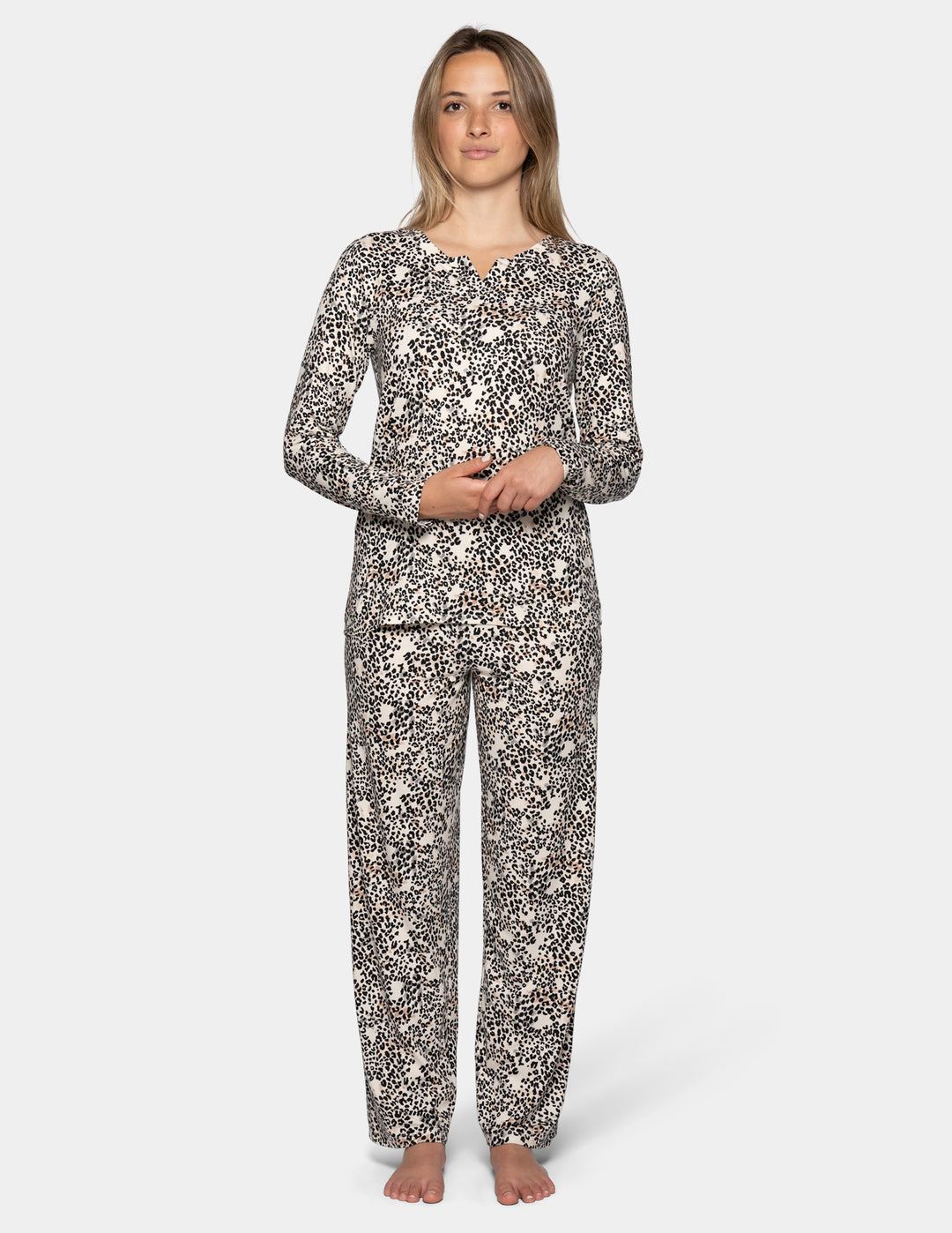 A model wearing a matching pajama set featuring a long sleeve top and full length pants with an animal print pattern.