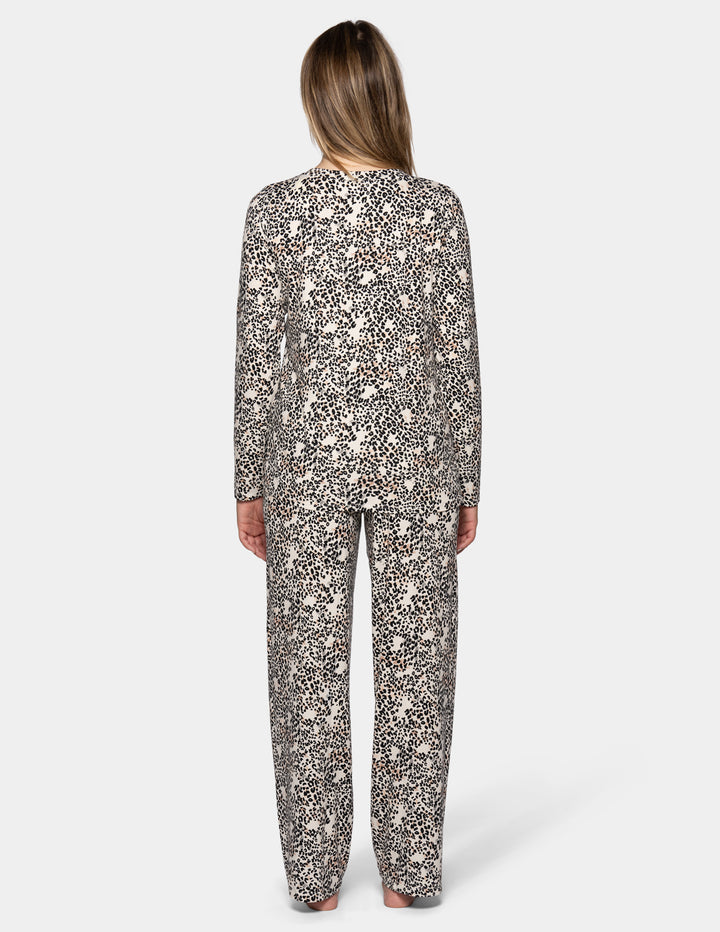 A backside view of model wearing a matching pajama set featuring a long sleeve top and full length pants with an animal print pattern.