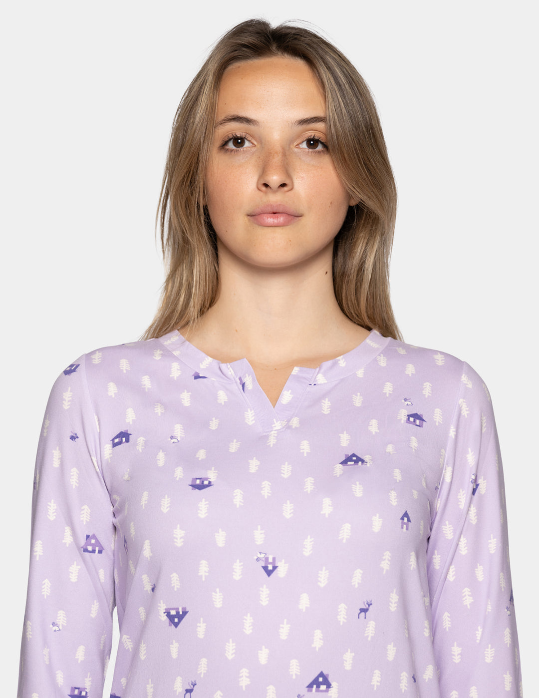 A woman wearing a long sleeve light lavender pajama top with a repeating pattern against a light gray background.