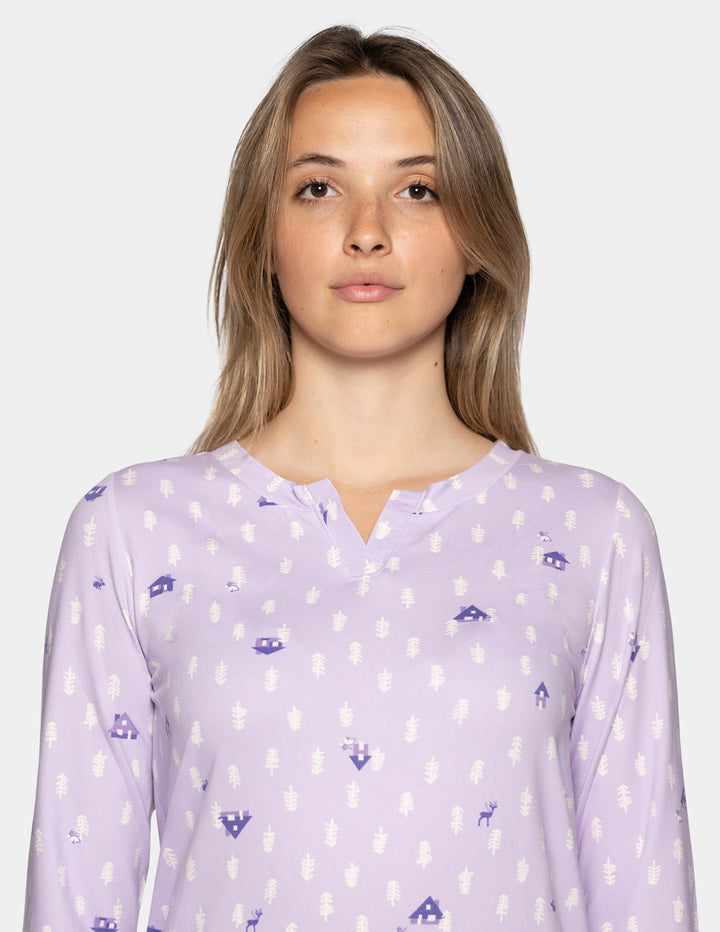 A woman wearing a long sleeve light lavender pajama top with a repeating pattern against a light gray background.