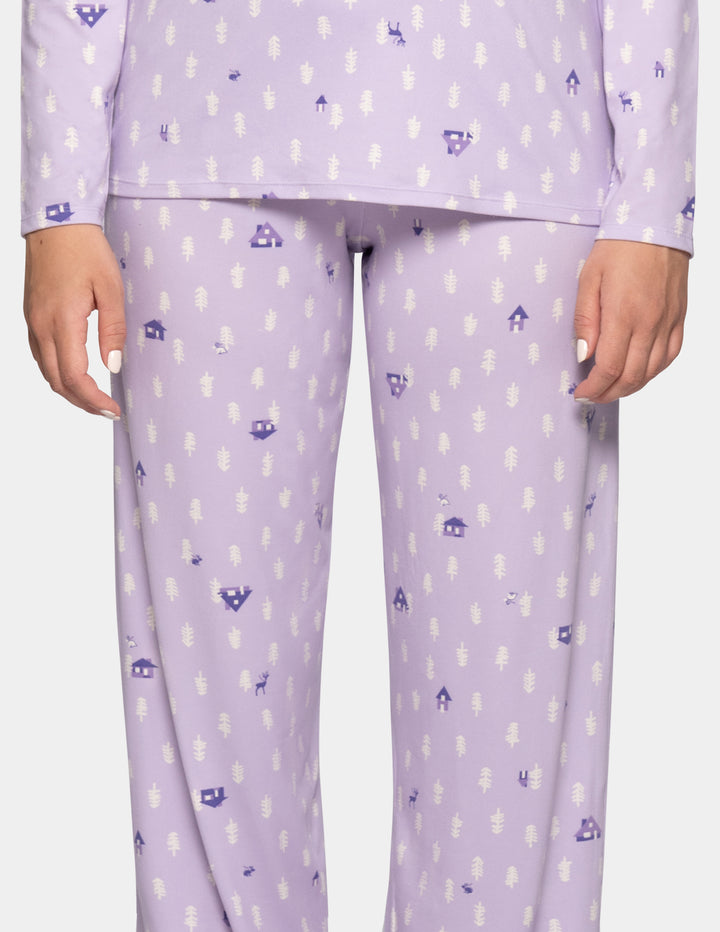 A model wearing long pajama pants in a light lavender color with a repeating pattern against a light gray background.