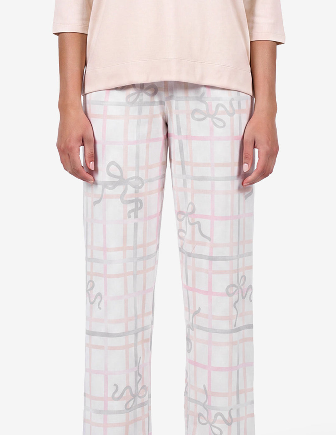 A model wearing a light pink pajama top and light gray pajama pants with a bow and stripe pattern against a light gray background.