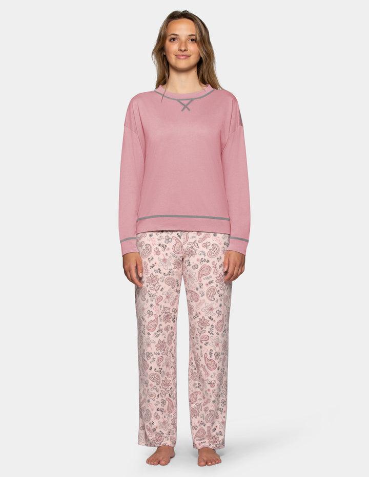 A model wearing a pink long sleeve pajama top and patterned pajama pants photographed against a light grey background.