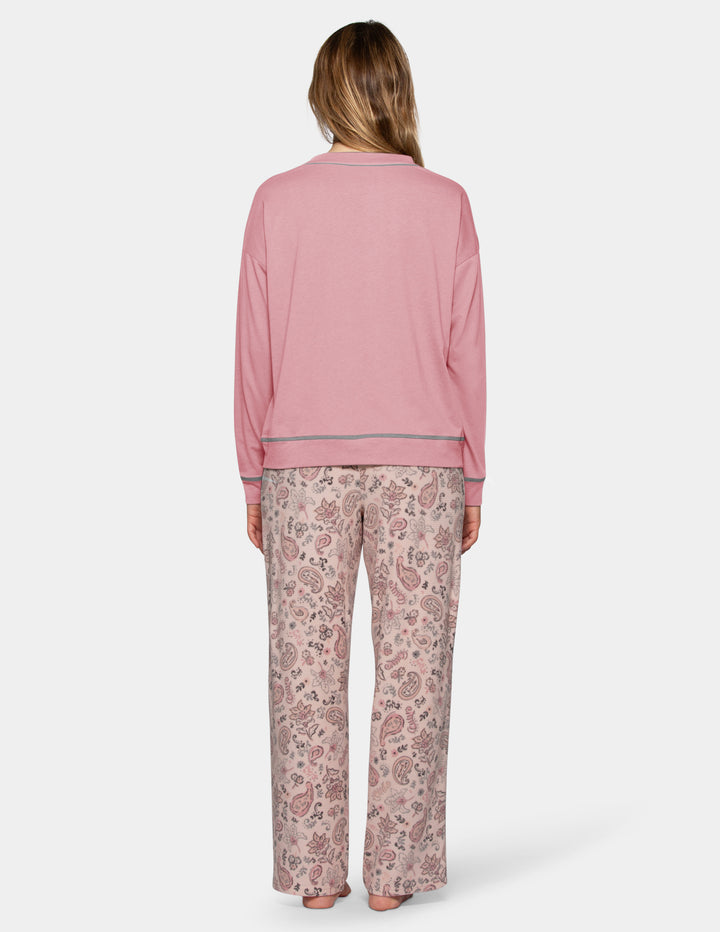 A backside view of a model wearing a pink long sleeve pajama top and patterned pajama pants photographed against a light grey background.