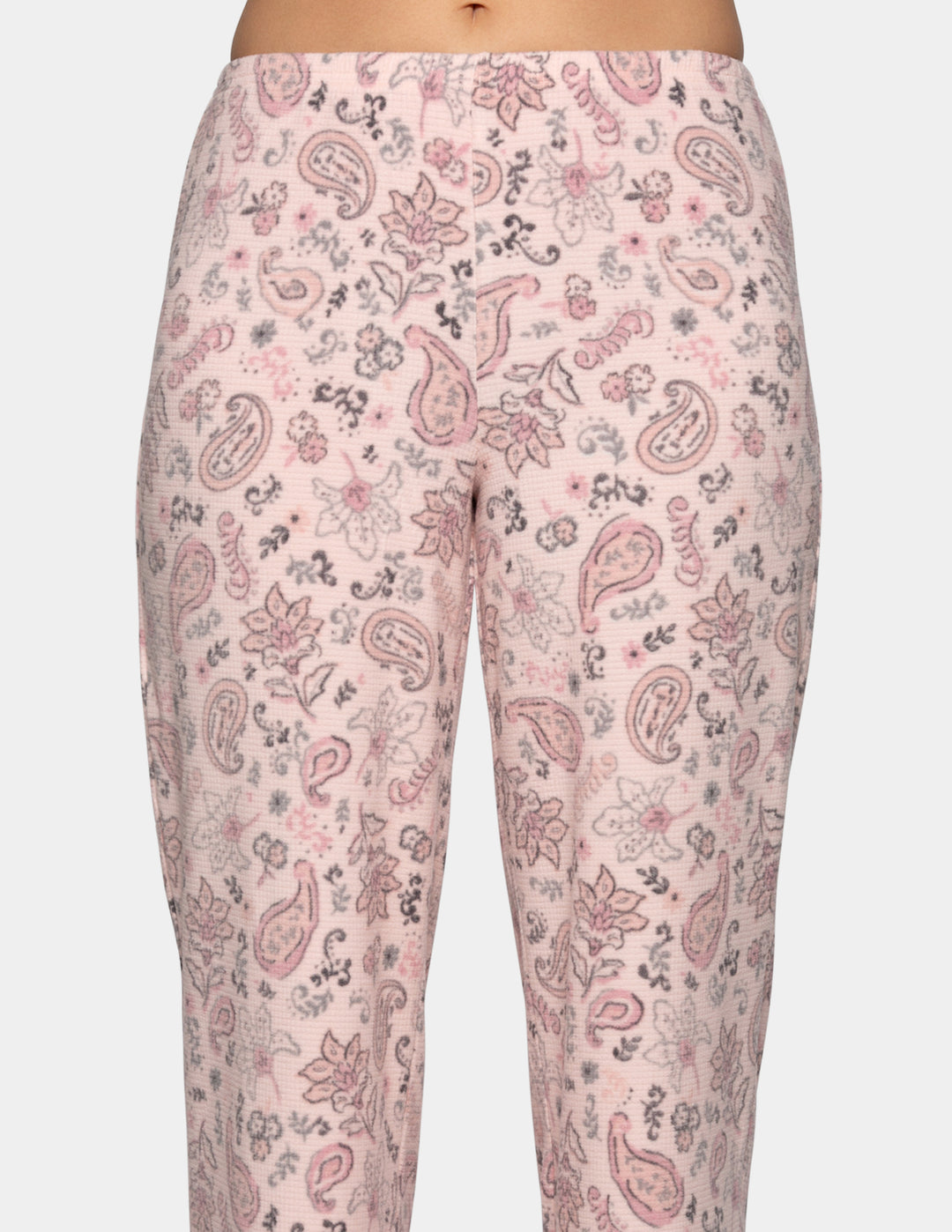 A closeup of a model wearing pink paisley patterned pajama pants.