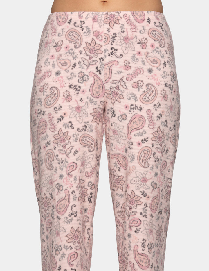 A closeup of a model wearing pink paisley patterned pajama pants.