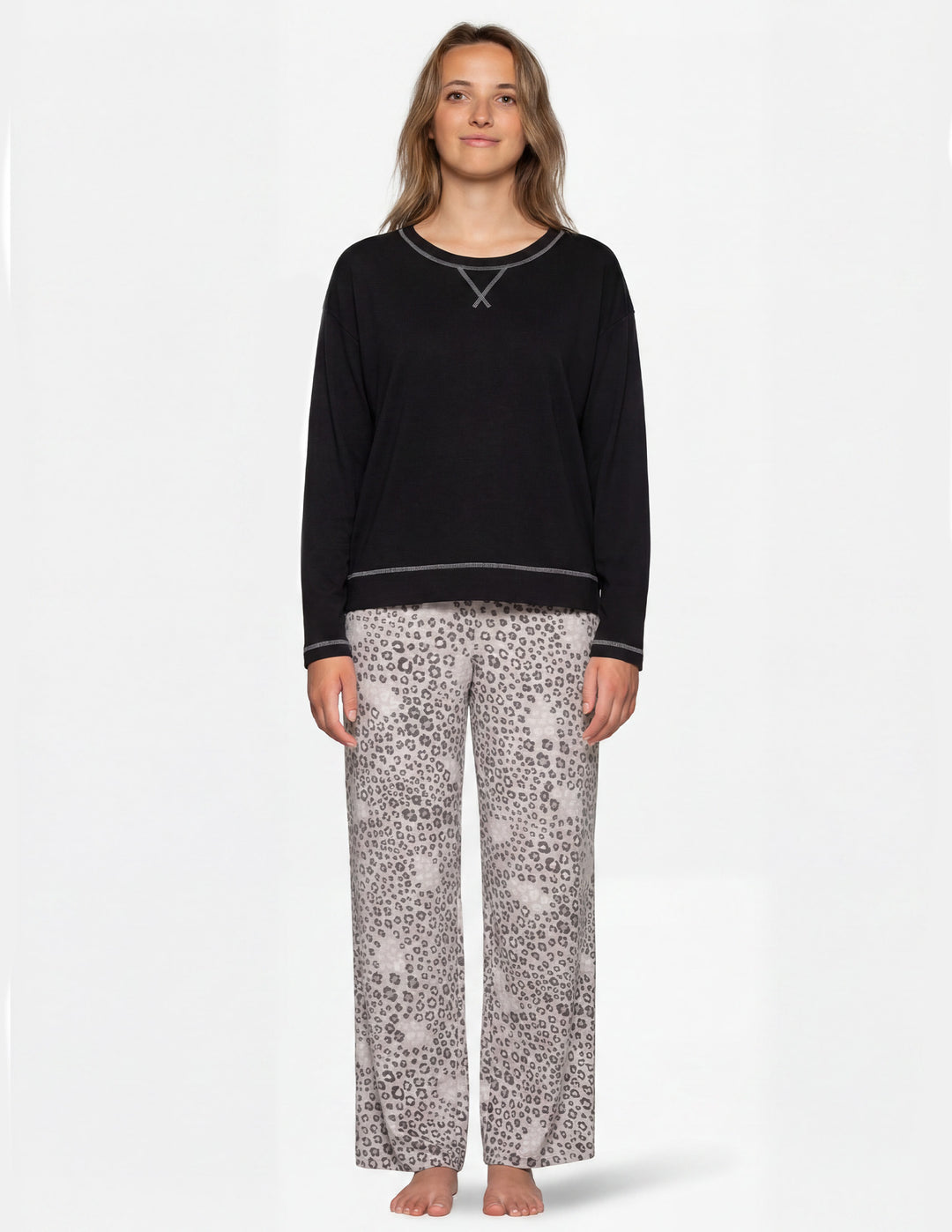 Woman wearing a black long sleeve pajama shirt and leopard print pajama pants.