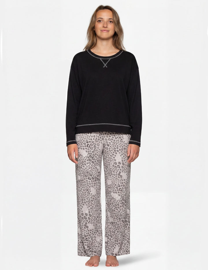 Woman wearing a black long sleeve pajama shirt and leopard print pajama pants.